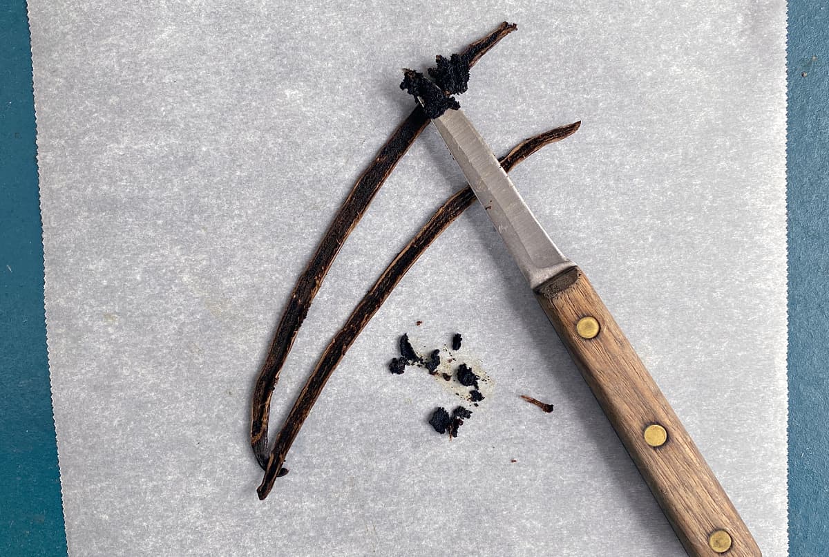 Split vanilla bean with a small knife. Vanilla bean seeds are scraped onto the end of the knife.