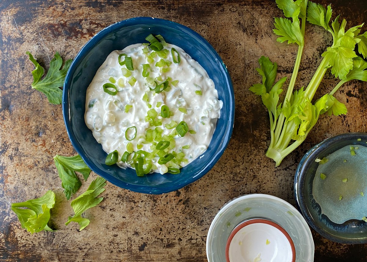 Blue Cheese Dip in a blue bowl, mixed and garnished with green onions.