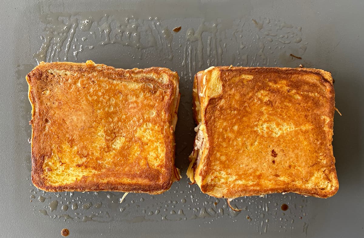 Two grilled sandwiches on heated skillet or electric grill. 