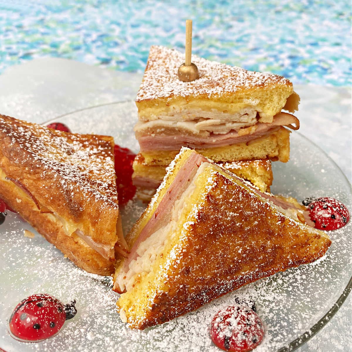 Ultimate Monte Cristo Sandwich, plated with gold ball sandwich skewer, dusted with powdered sugar. 