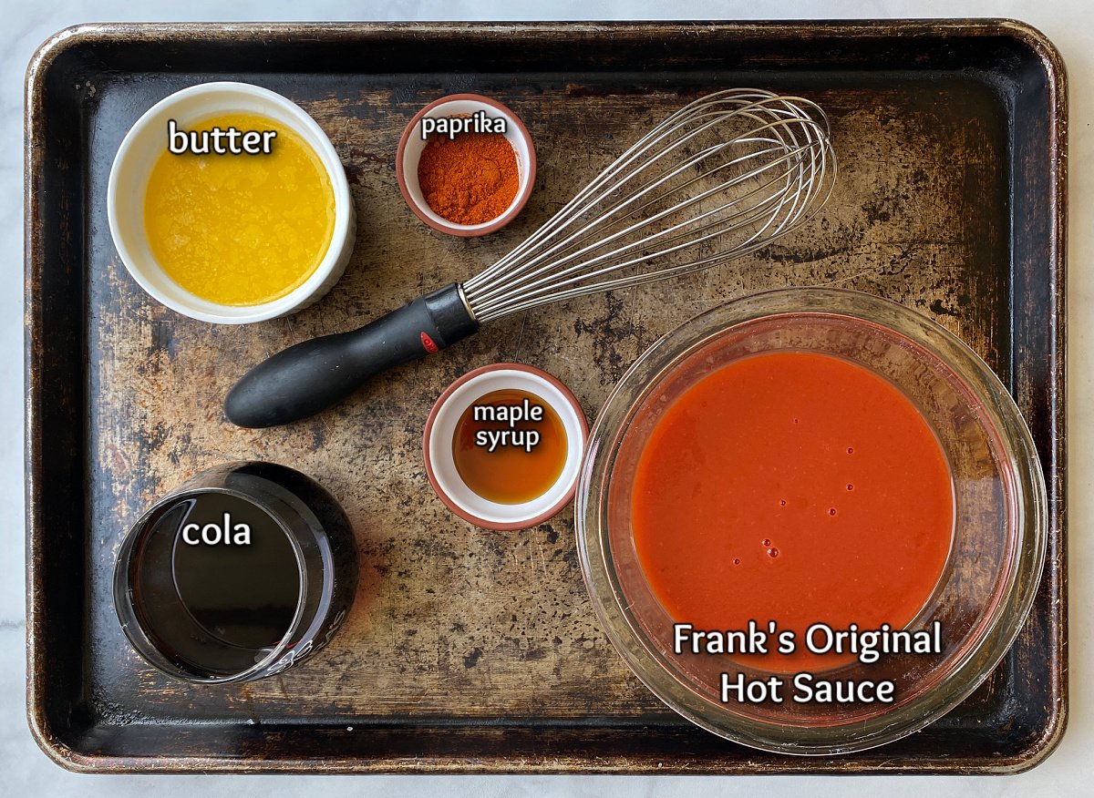 Buffalo wing marinade ingredients and large whisk on an old baking tray. 