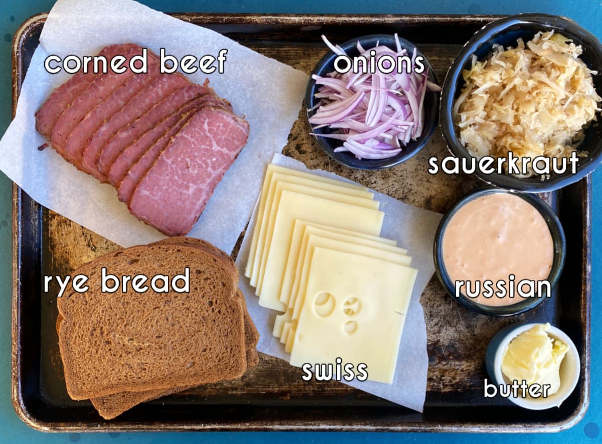 Rueben sandwich ingredients: corned beef, sauerkraut, Swiss, Russian dressing, butter, onions.