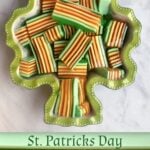 Shamrock shaped ceramic dish filled with bar cuts of layered jello. Colors green, orange, and yellow. Pin text reads, St Patrick's Day Layered Jello.