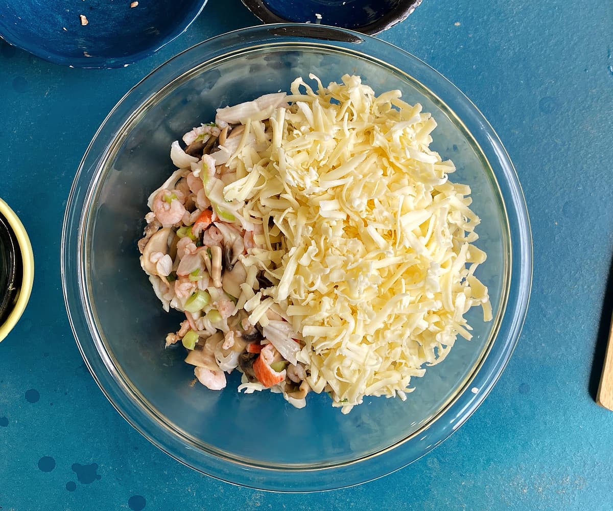 seafood mix and cheese in a glass mixing bowl.