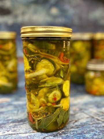 Four Bread & Butter Pickles in jars on a blue counter, after processing.