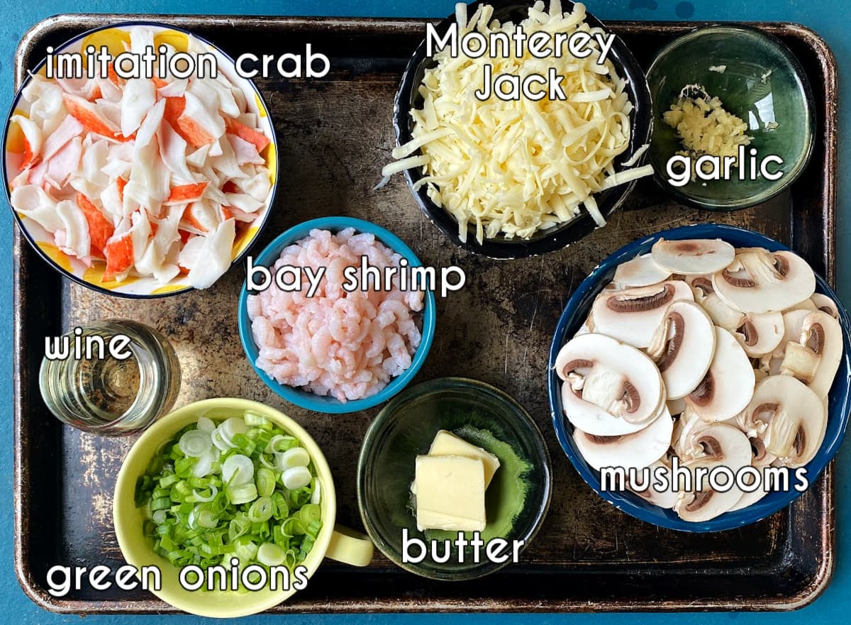 Seafood enchilada ingredients, labeled: imitation crab, bay shrimp, green onions, butter, mushrooms, garlic, green onions, wine.