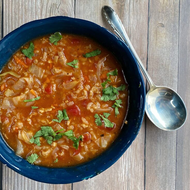 Overhead shot of cabbage roll soup in a hand-built clay bowl. Spoon to the side.