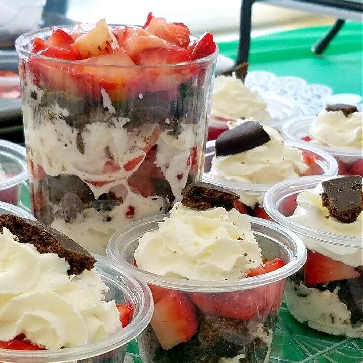 Clear plastic cups filled with chocolate-mint cookies, whipped cream, and strawberries. 