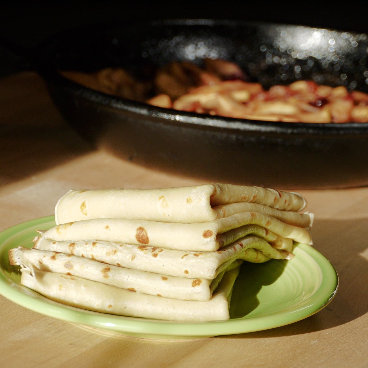 Five crepes folded in quarters and stacked on a small plate.