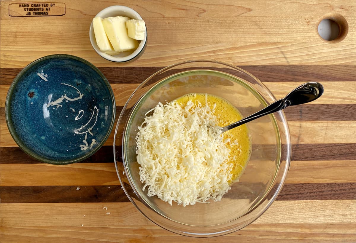 A small mixing bowl with egg mixture and cheese. 