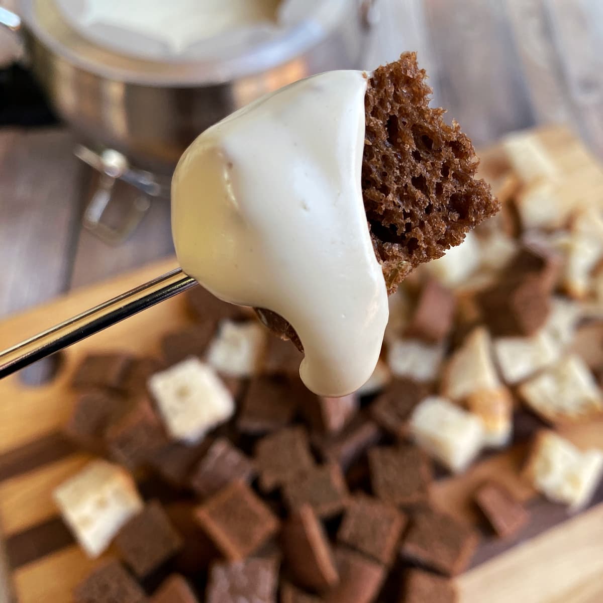 Cheese fondue dipped rye bread cube on the end of a metal skewer. 
