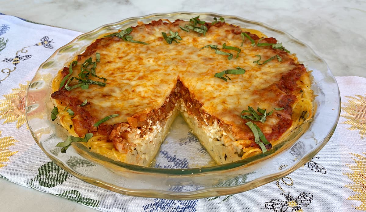 Baked spaghetti pie in glass pie dish. A single slice has been removed. 