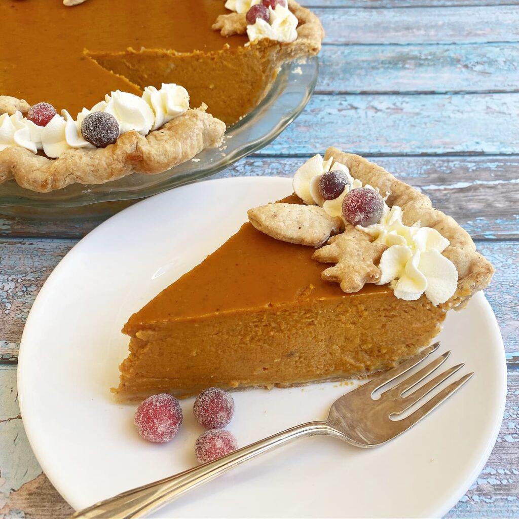 Slice of deep dish pumpkin pie on a white dessert plate.