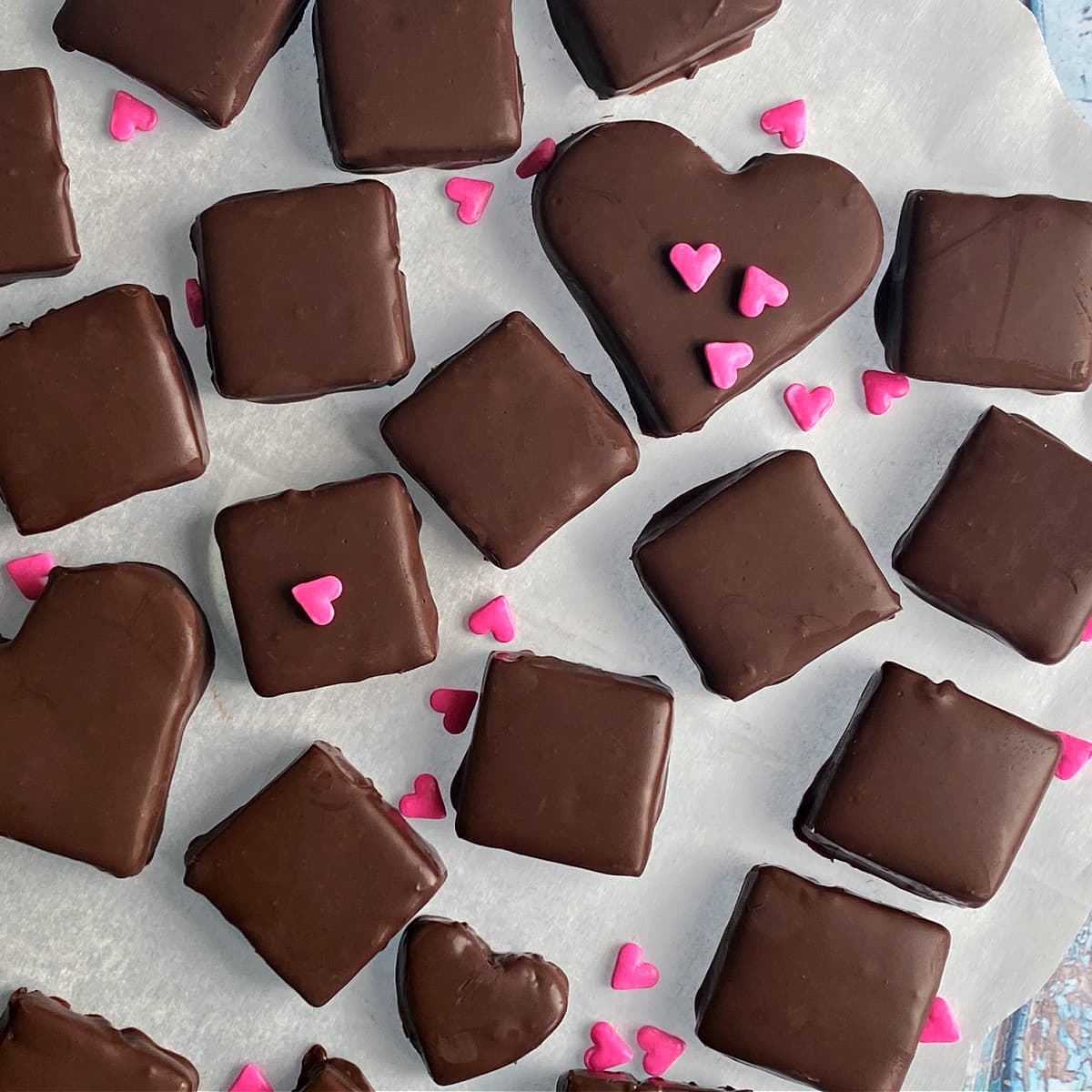 Dipped Bavarian mint chocolates on parchment, with small pink hearts sprinkled around for color. 