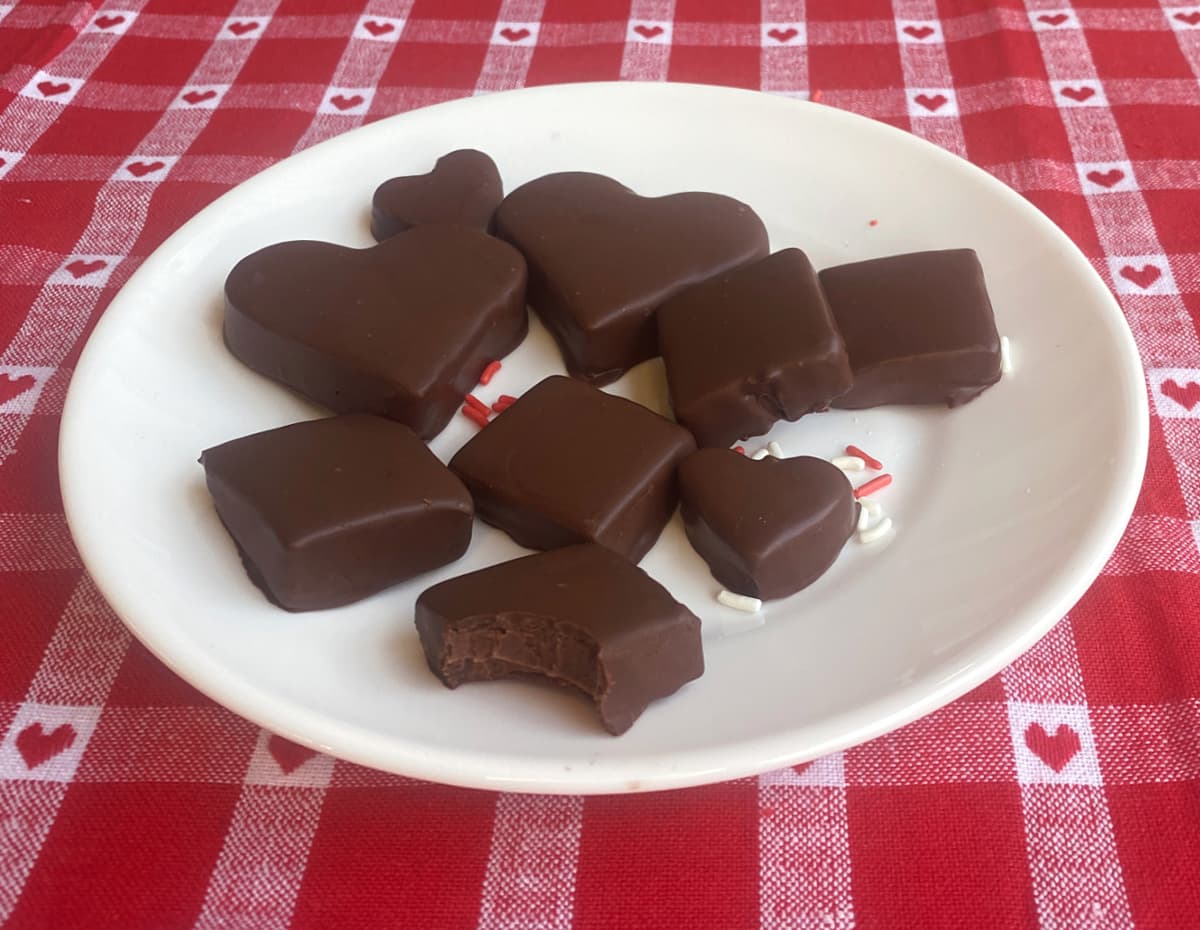Plate of dipped Bavarian mints. One piece has a bite taken out, revealing chocolate meltaway center.