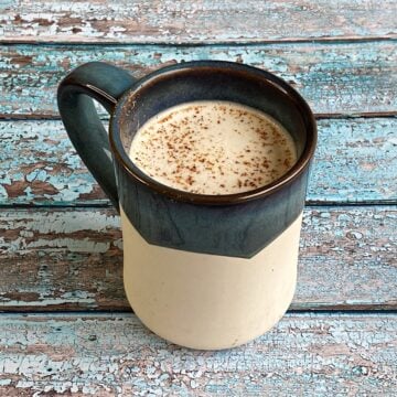 Large ceramic mug with a creamy beverage topped with grated nutmeg.