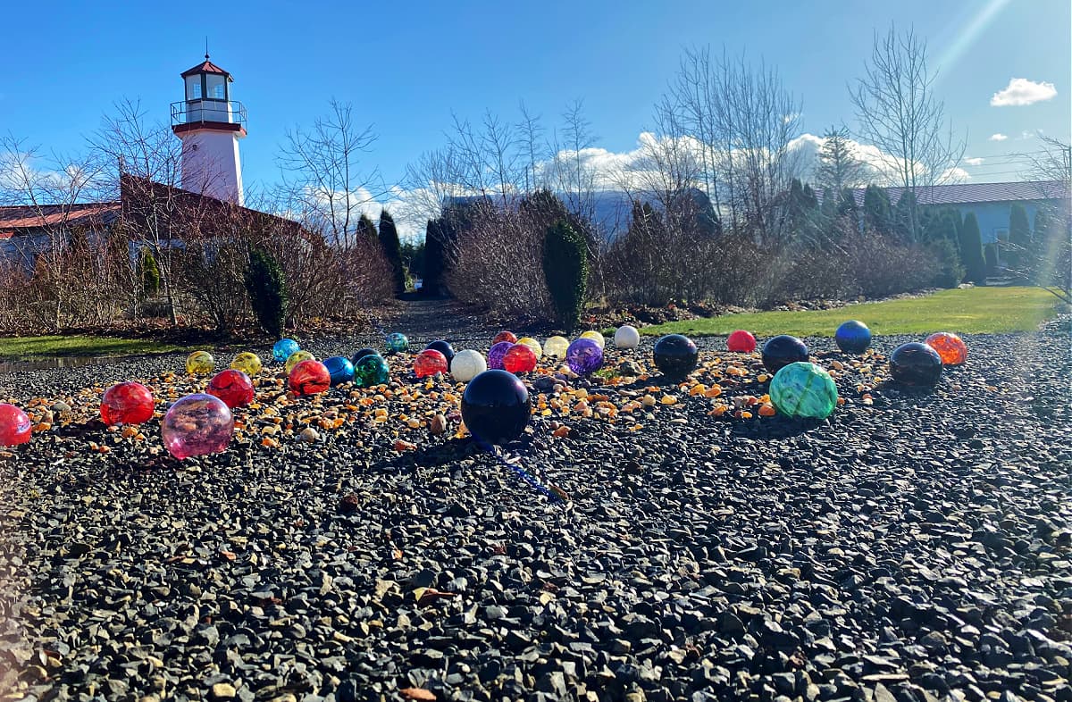 Colorful glass floats arranged in a pattern on pea gravel.