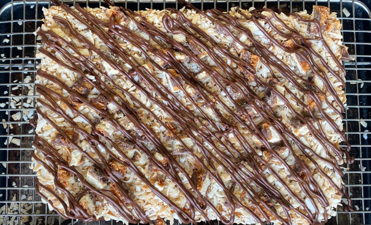 Cheesecake bars in large flat layer, with chocolate drizzled on.