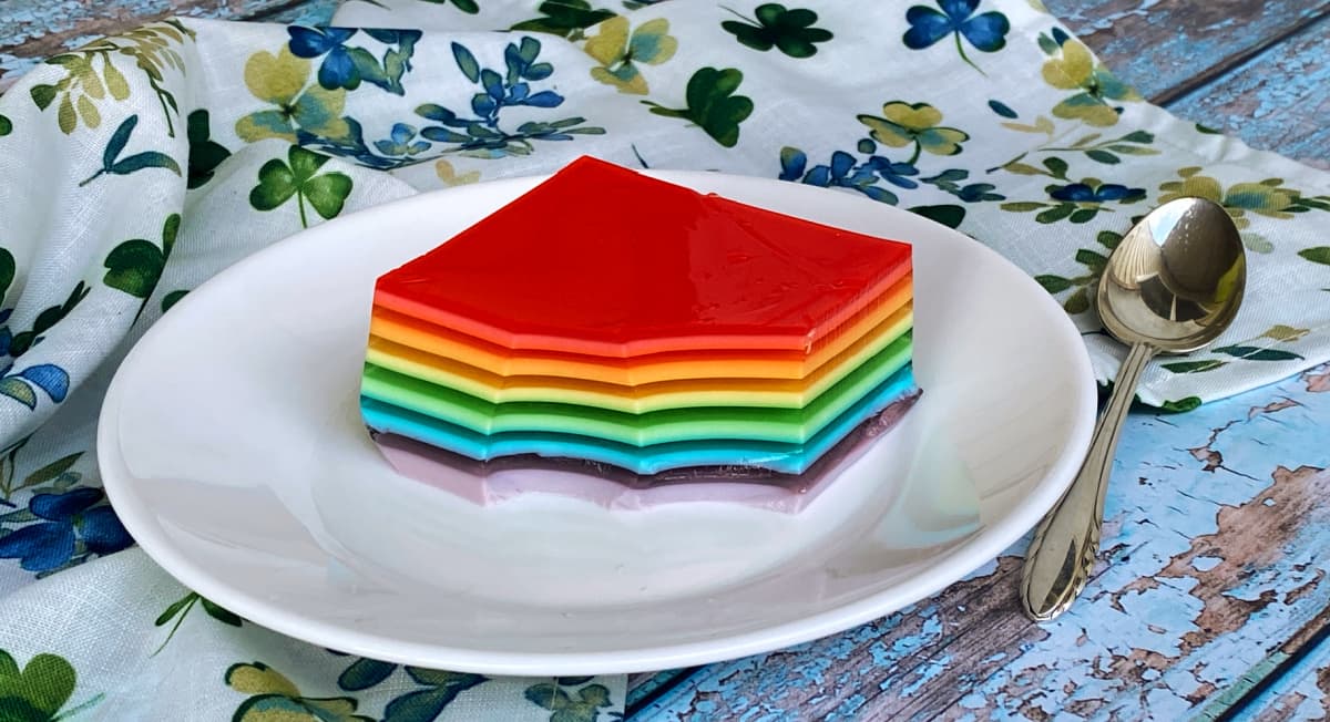 Single serving of rainbow jello on a small plate; spoon to the side. 
