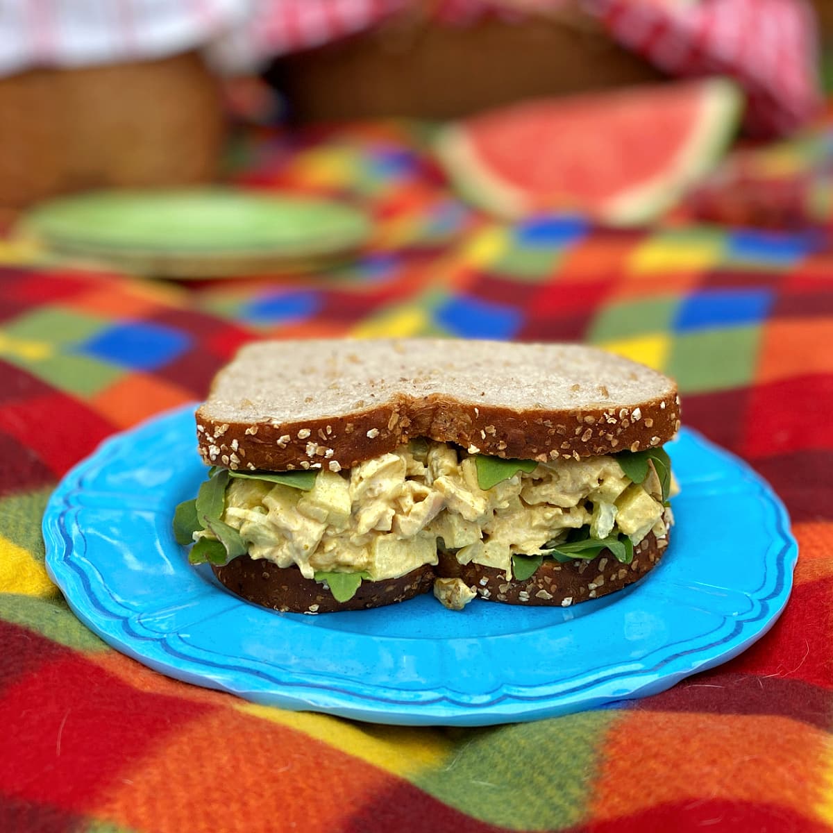 Curried Chicken Salad in a sandwich, on a checked picnic blanket. 