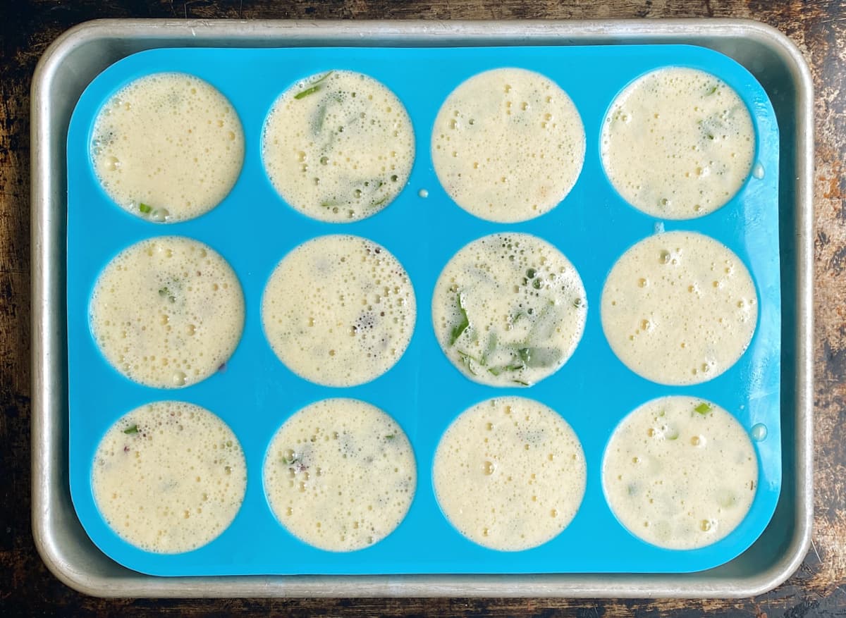 A silicone muffin pan filled with egg mixture, uncooked. 