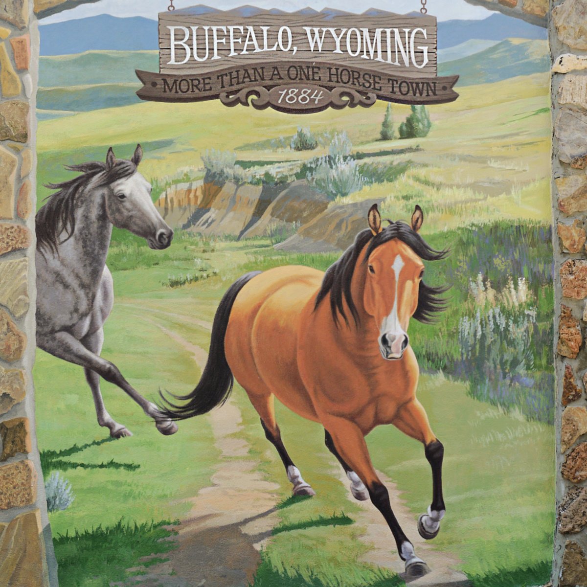 Mural of two horses on the move, coming toward the viewer. Text painted above reads: Buffalo, Wyoming - more than just a one horse town - 1884.