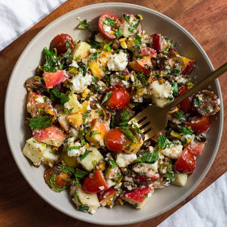 Overhead shot of peach salad with apples, feta, and basil.