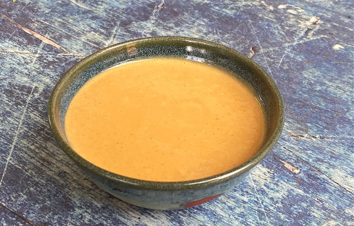 45-degree shot of a small bowl of peanut sauce.