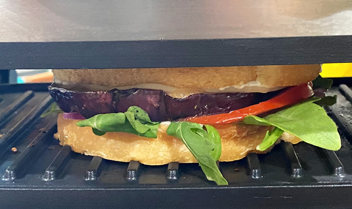 Closeup of sandwich grilling in a panini press. 