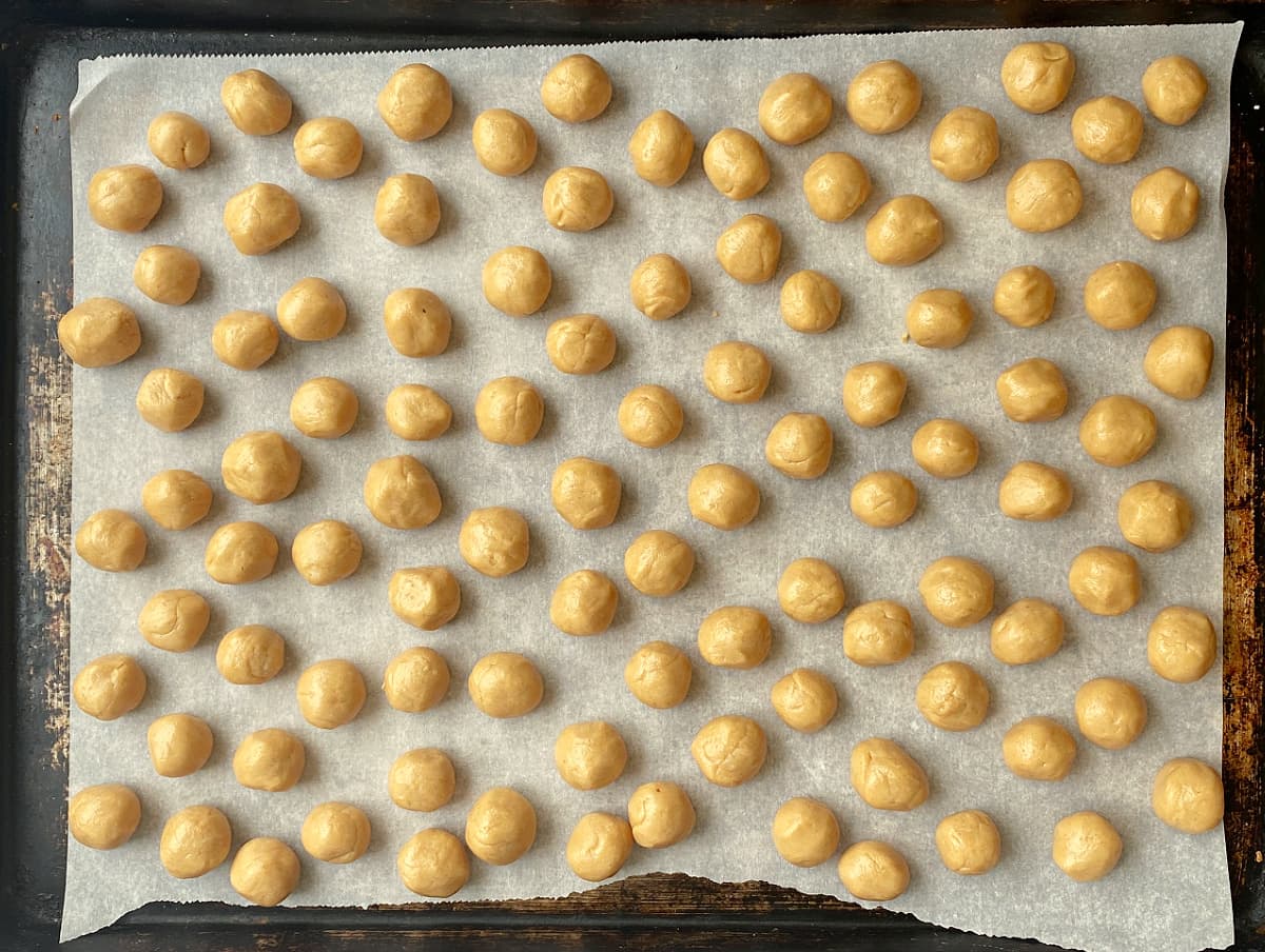 Peanut butter balls rolled and chilling on parchment covered tray.