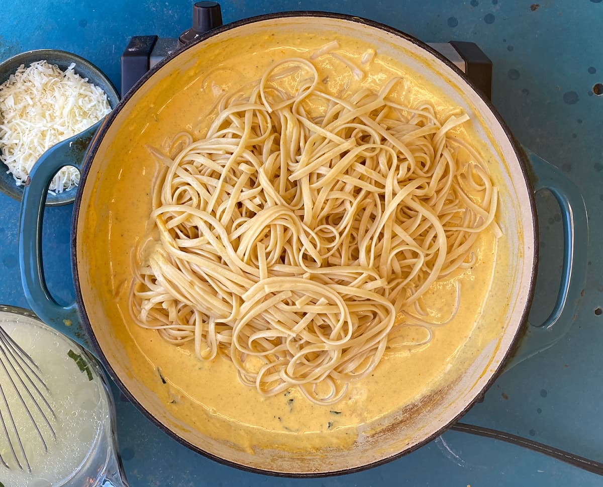 Linguini added to pasta sauce in skillet.