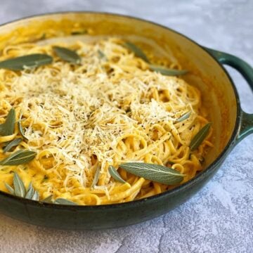 Closeup of pumpkin pasta garnished with parmesan and fresh sage; ready to serve.