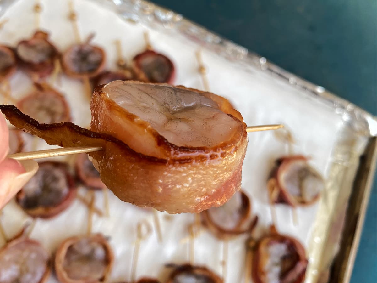 Close-up of a raw shrimp wrapped with bacon, skewered and ready to broil.