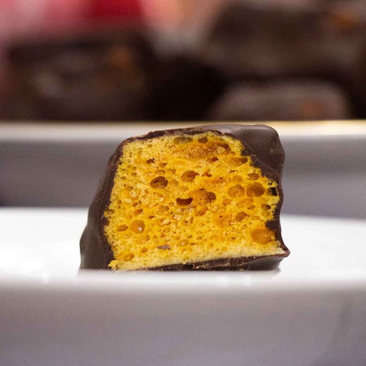 Large piece of Homemade Sponge Candy (or seafoam) broken open on a plate.