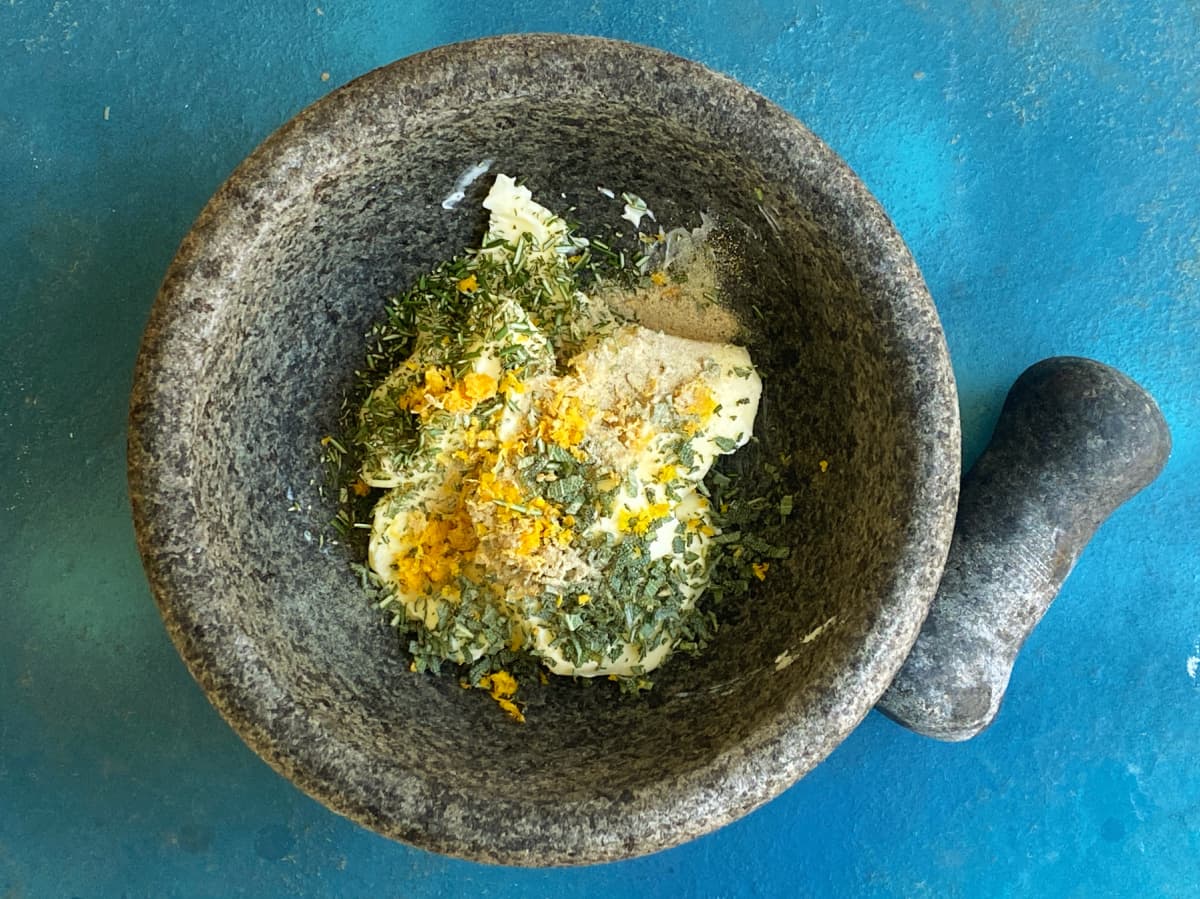 Butter and aromatic ingredients in a molcajete, unmixed.