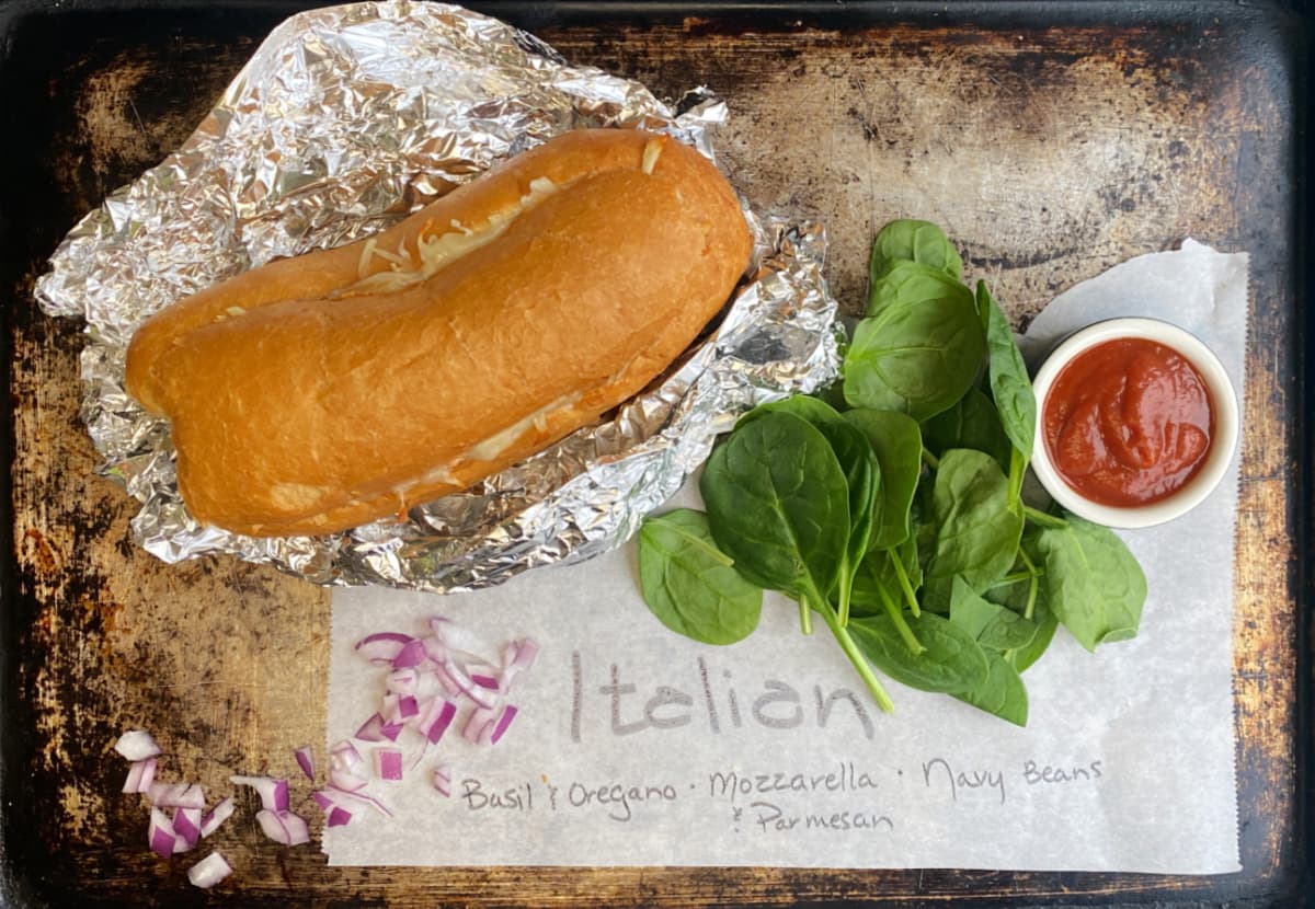 Italian french bread sandwich with garnish ideas on a piece of parchment.