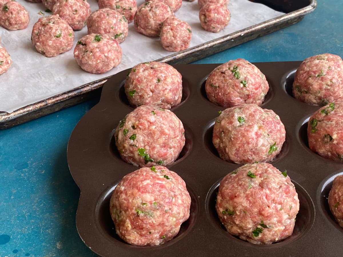 Meatballs formed and resting on a recessed meatball tray. 