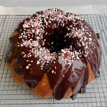 45-degree shot of Peppermint White Chocolate Bundt Cake with ganache and peppermint sprinkles added to top.