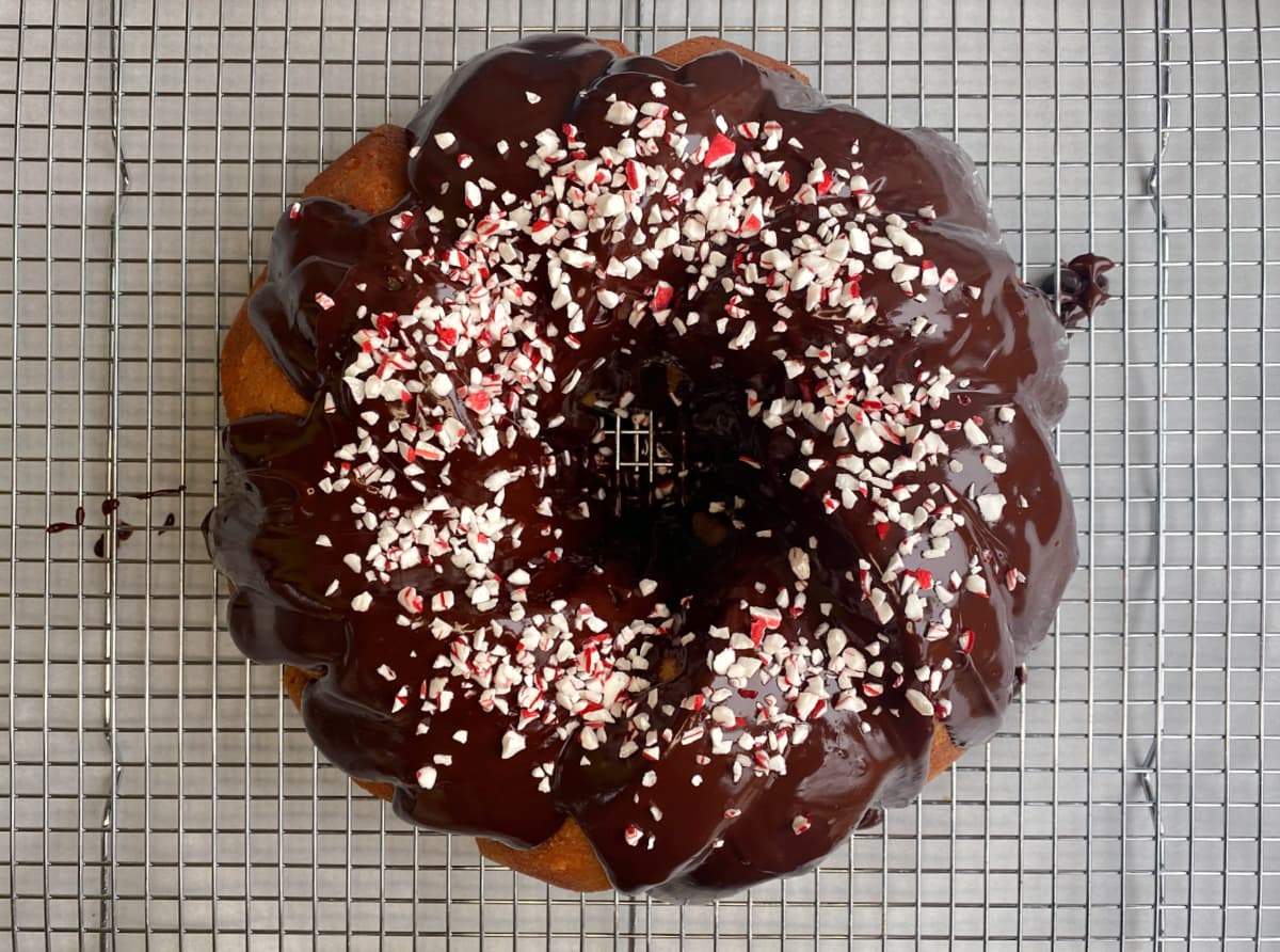 Overhead shot of Peppermint White Chocolate Bundt Cake with ganache and peppermint sprinkles added to top.