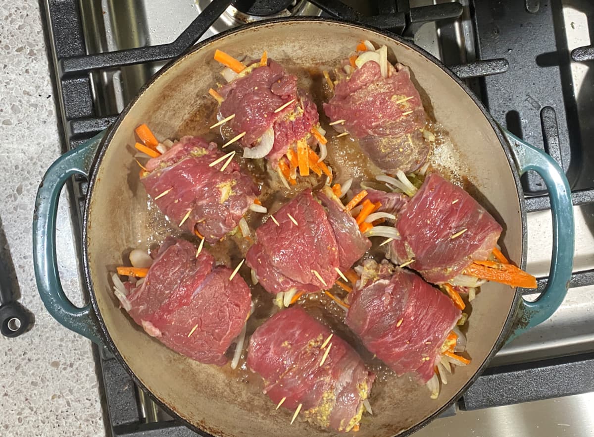 Beef rolls searing in cast iron skillet.