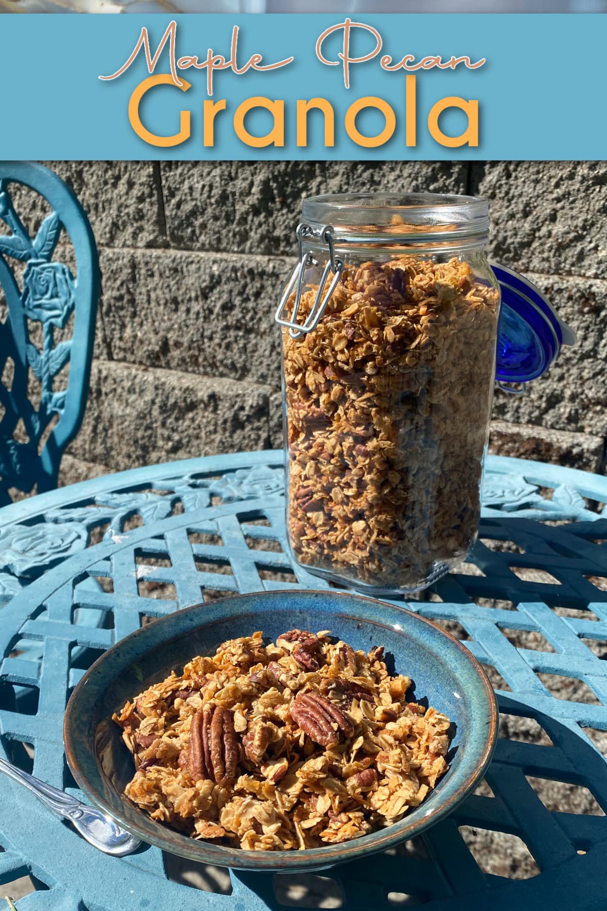 A bowl of pecan granola in a small bowl, setting on an outdoor bistro table. Pin text reads: Maple Pecan Granola