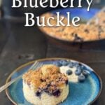 A round-cut piece of blueberry buckle on a plate, with a dollap of yogurt and a sprinkle of fresh blueberries on the side. The remaining unserved buckle is in the background. Pin text reads "Old fashioned Blueberry Buckle | Moist Cake with Crumble Topping • Easy Vintage Recipe".
