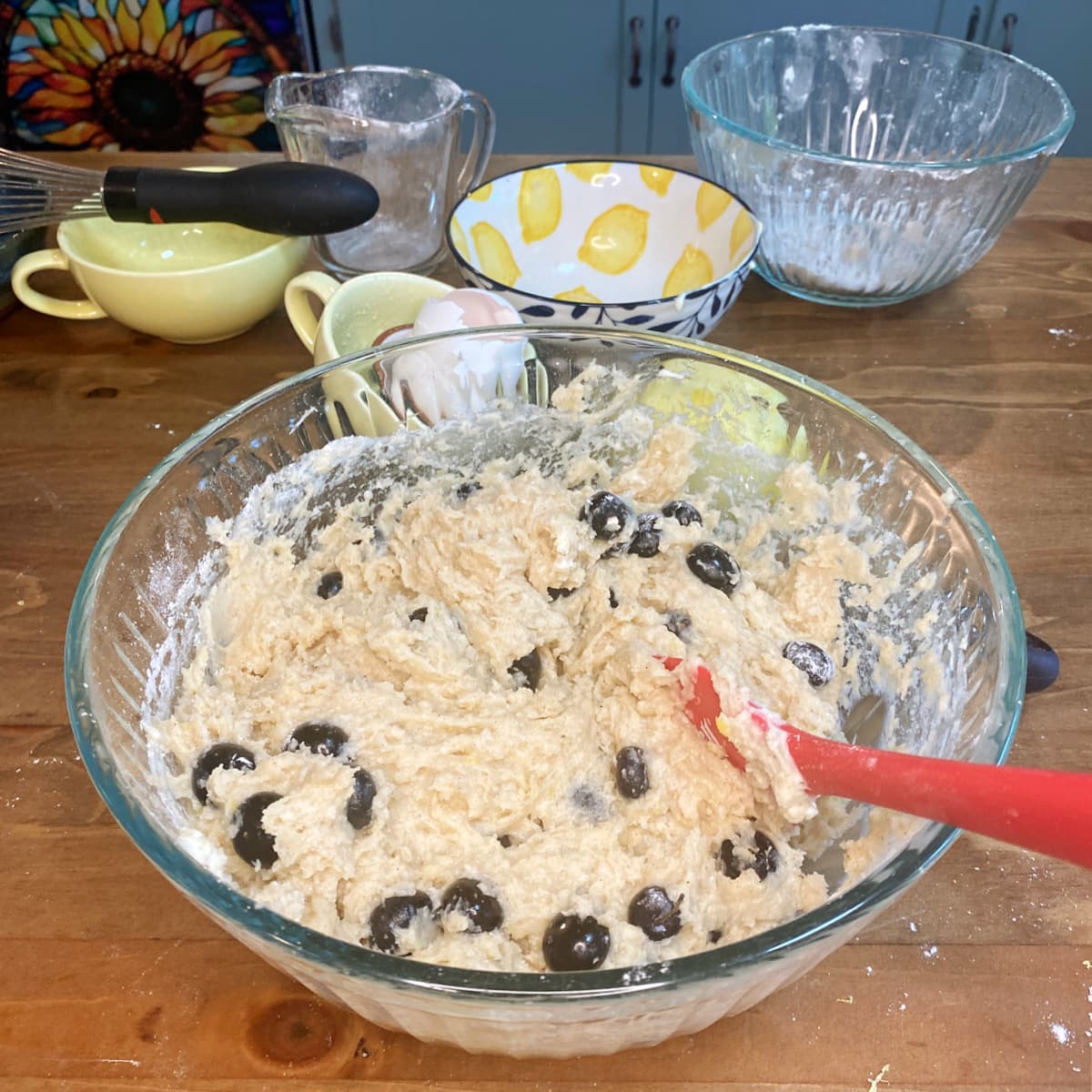 Fresh blueberries being gently folded into gluten-free lemon muffin batter.