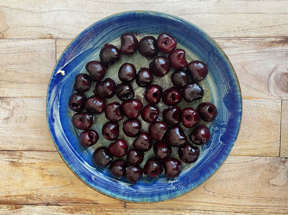 Buttered pie plate with raw cherries covering the bottom.