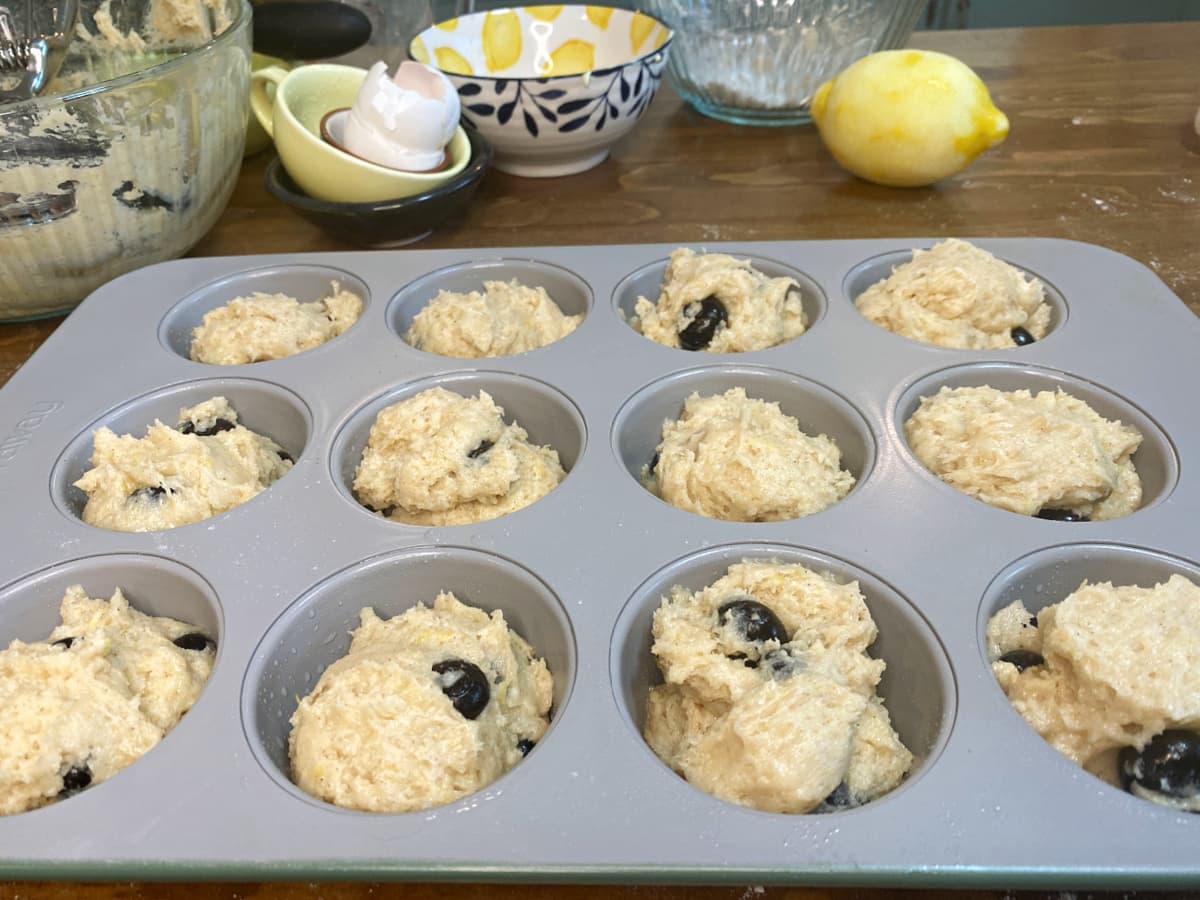 Muffin tin filled with gluten-free lemon blueberry muffin batter, ready to bake.