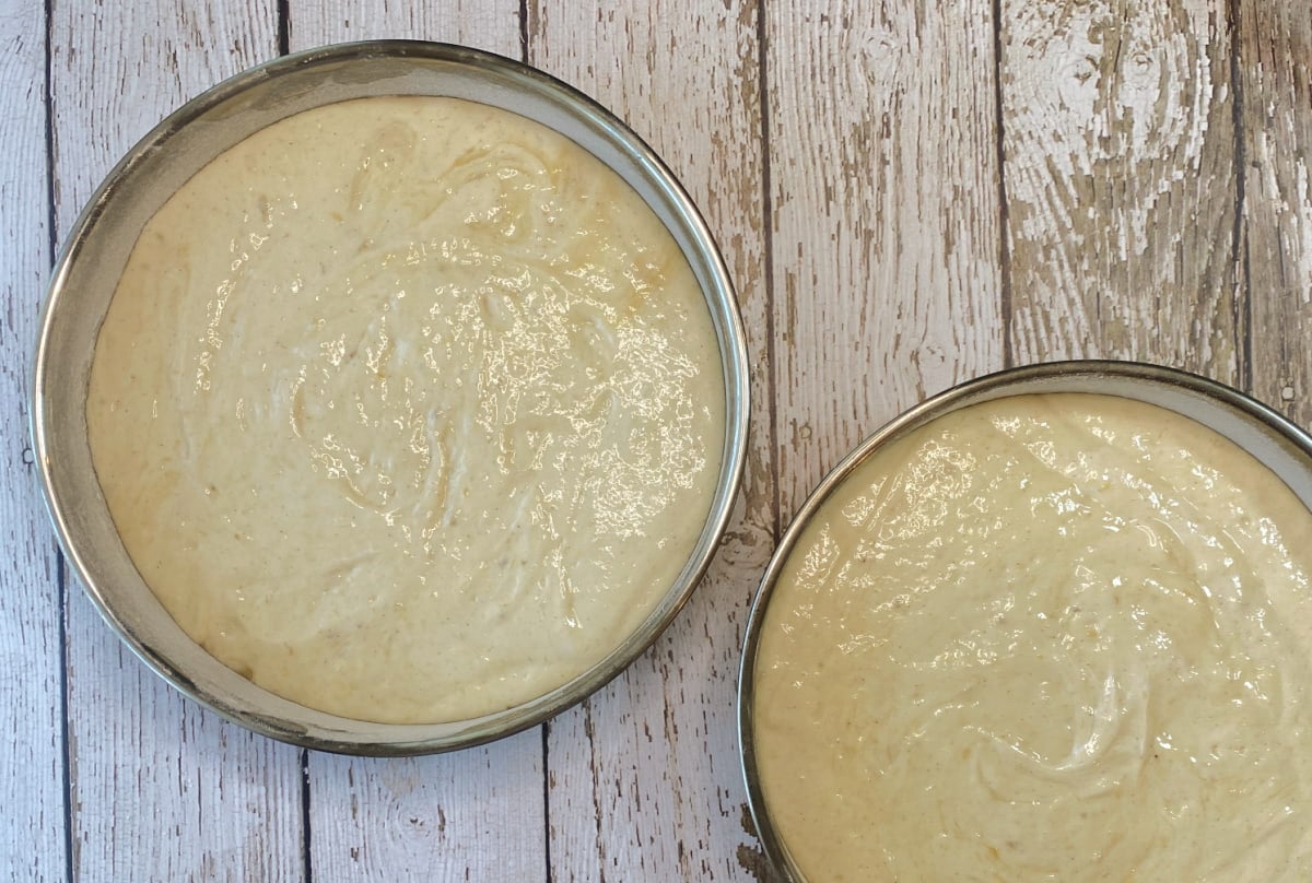 Banana chiffon cake batter poured evenly into round cake pans.