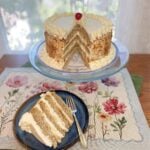 Whole Banana Cream Chiffon Cake on a stand, topped with whipped cream and banana slices. Slice of cake on small plate, showing fluffy layers, fresh banana slices, and whipped cream frosting.