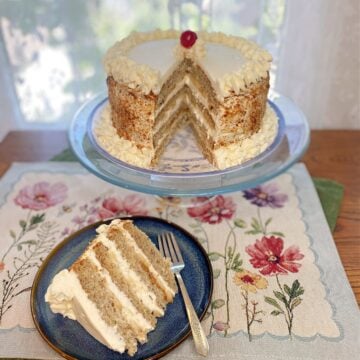 Whole Banana Cream Chiffon Cake on a stand, topped with whipped cream and banana slices. Slice of cake on small plate, showing fluffy layers, fresh banana slices, and whipped cream frosting.
