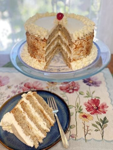 Whole Banana Cream Chiffon Cake on a stand, topped with whipped cream and banana slices. Slice of cake on small plate, showing fluffy layers, fresh banana slices, and whipped cream frosting.