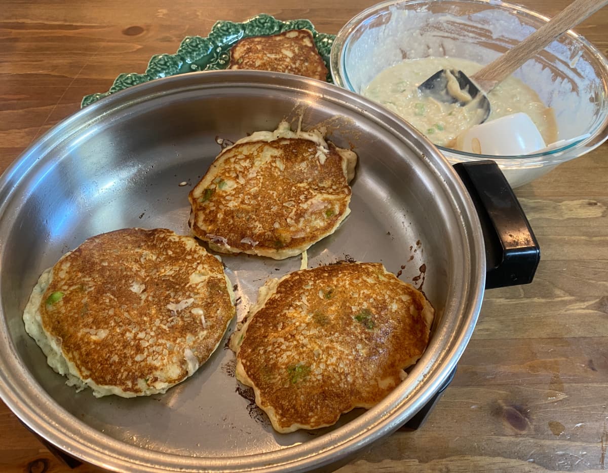 Spoonful of boxty batter being added to a hot skillet.